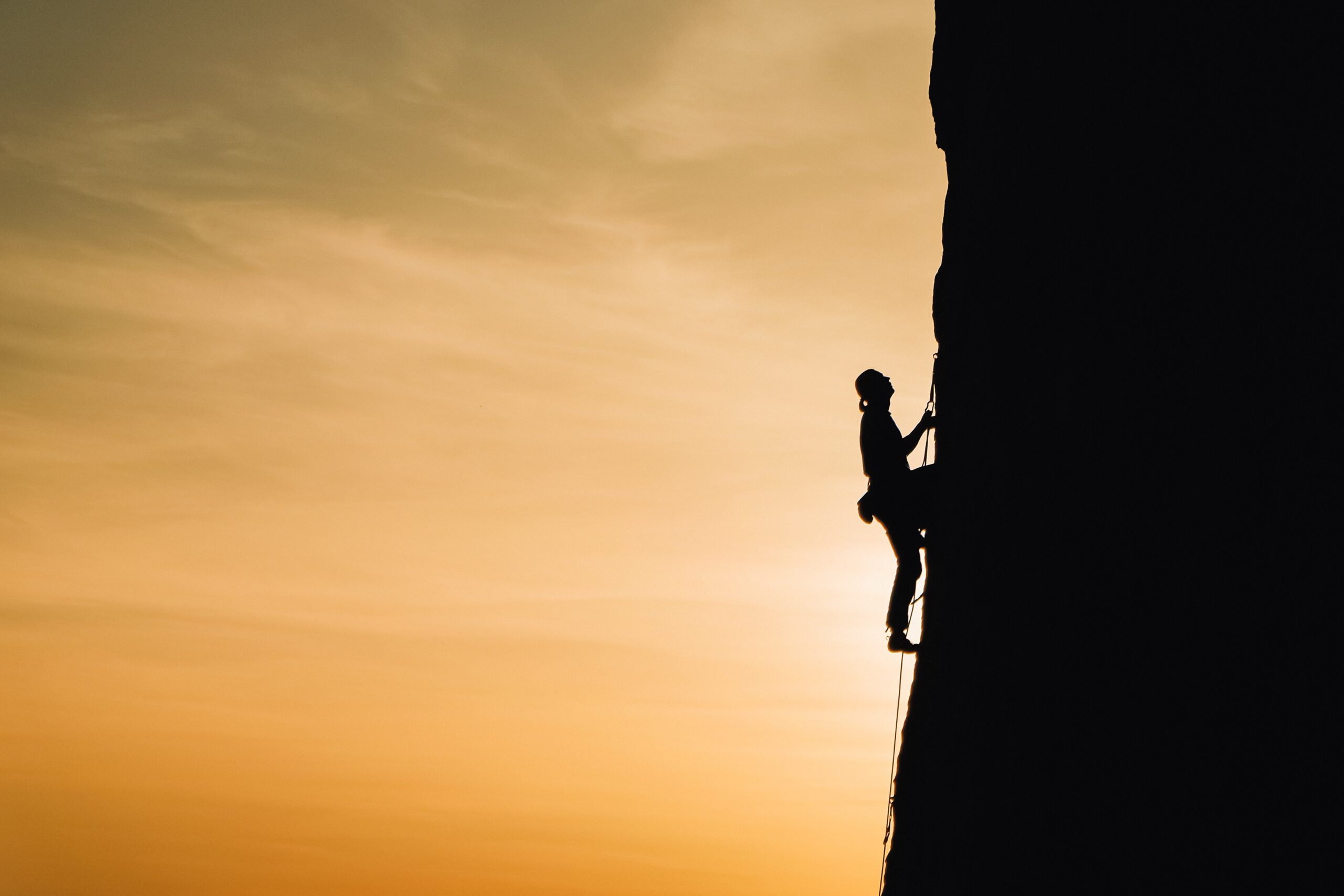 Silhouette of a person climbing a mountain