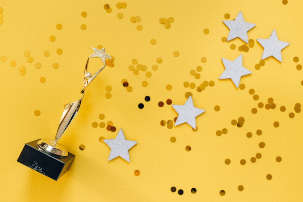 Trophy and stars and glitter on yellow background.